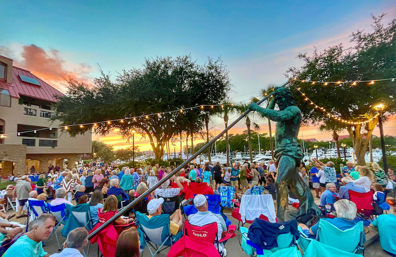 crowd gathers under the Neptune statue at sunset for Shelter Cove Music & Taste